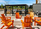Thumbnail 69 of 98 - A set of orange Adirondack chairs surrounding the fire pit at The Beaumont Apartments, Bozeman, MT