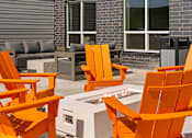 Thumbnail 68 of 98 - A set of orange chairs are arranged around a fire pit at The Beaumont Apartments, MT 59715