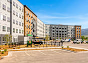 Thumbnail 57 of 98 - A parking lot in front of a multi-story apartment building at The Beaumont Apartments, MT 59715