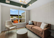 Thumbnail 44 of 98 - Cozy coworking space with a brown couch, a chair, and a small ottoman at The Beaumont Apartments, Bozeman, MT