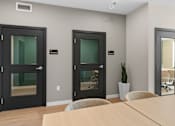 Thumbnail 37 of 98 - Three black doors with glass panels are in a room with a wooden table and chairs at The Beaumont Apartments, Bozeman