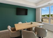 Thumbnail 47 of 98 - A conference room with a table and chairs and a television on the wall at The Beaumont Apartments, Bozeman, Montana 59715