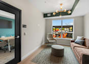 Thumbnail 45 of 98 - A room with a couch, chair, and table with a view of the outside at The Beaumont Apartments, MT 59715