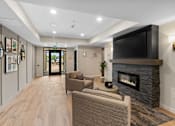 Thumbnail 49 of 98 - Resident lounging area with two cozy chairs, a fireplace, and a television at The Beaumont Apartments, Montana, 59715