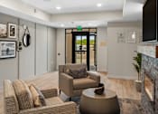Thumbnail 52 of 98 - Cozy resident lounge space with two lounge chairs and an ottoman in front of the fireplace at The Beaumont Apartments, Bozeman, MT