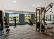 Thumbnail 31 of 98 - A gym with a variety of equipment including a leg press machine, a chest press machine, and a squat rack at The Beaumont Apartments, Montana