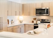 Thumbnail 1 of 52 - A kitchen with wooden cabinets and a white countertop.at Copestone Apartments, Garden City, 59808