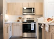 Thumbnail 25 of 52 - A modern kitchen with wooden cabinets and stainless steel appliances.at Copestone Apartments, Garden City, ID