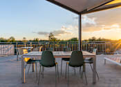 Thumbnail 43 of 52 - A table with chairs is set up on a wooden deck.at Copestone Apartments, Idaho