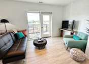Thumbnail 7 of 23 - A living room with a black leather couch, a green chair, and a flat screen TV at Cannery Flats, Bozeman, Montana