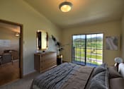 Thumbnail 3 of 18 - A bedroom with a large bed and a view of the outdoors through the window.