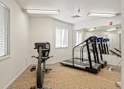 Thumbnail 7 of 28 - A room with a treadmill and a stationary bike.
