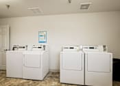 Thumbnail 17 of 28 - Two white front loading washing machines in a laundry room.