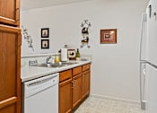 Thumbnail 15 of 28 - A kitchen with white appliances and wooden cabinets.