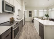 Thumbnail 13 of 26 - an open kitchen and living room with a large island and a stove and a microwave