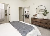 Thumbnail 11 of 26 - a bedroom with a bed and a dresser and a bathroom