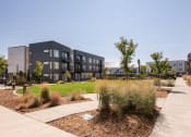 Thumbnail 21 of 26 - an exterior view of an apartment complex with a sidewalk and landscaping