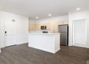 Thumbnail 29 of 29 - A kitchen with white cabinets and a white island with a refrigerator on the right side.