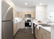 Thumbnail 9 of 29 - A modern kitchen with a stainless steel refrigerator and wooden cabinets.