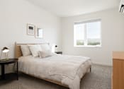 Thumbnail 12 of 29 - A bedroom with a bed, nightstand, and window.
