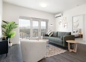 Thumbnail 11 of 29 - A living room with a green couch and a white ottoman.