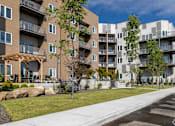 Thumbnail 16 of 29 - Apartment buildings with balconies and trees in front.