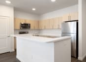 Thumbnail 22 of 29 - A kitchen with white countertops and a stainless steel refrigerator.