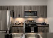 Thumbnail 8 of 28 - a kitchen with stainless steel appliances and wooden cabinets at Crosshatch, Garden City, ID, 83714