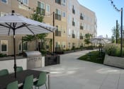 Thumbnail 19 of 28 - a patio with tables and umbrellas in front of an apartment building at Crosshatch, Garden City, ID, 83714