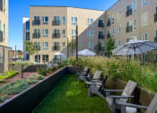 Thumbnail 20 of 28 - a patio with chairs and an umbrella in front of an apartment building at Crosshatch, Idaho, 83714