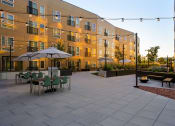 Thumbnail 1 of 28 - a courtyard with tables and umbrellas in front of an apartment building at Crosshatch, Garden City, ID, 83714