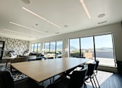 Thumbnail 17 of 23 - A conference room with a long table and chairs, a patterned wall, and a view of the mountains outside the windows at Cannery Flats, Bozeman, Montana