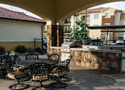 Thumbnail 19 of 28 - A patio with a table and chairs is in front of a building.