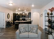 Thumbnail 2 of 28 - A grey couch with a striped pillow is in the middle of a kitchen and dining room.