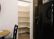 Thumbnail 16 of 28 - A black refrigerator is in a kitchen with a table and a chair.