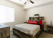 Thumbnail 3 of 28 - A bedroom with a bed, nightstand, and a ceiling fan.
