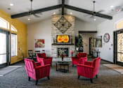 Thumbnail 14 of 28 - A living room with a fireplace and red chairs.