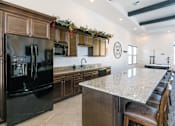Thumbnail 9 of 28 - A kitchen with a black refrigerator and brown cabinets.