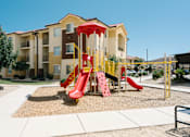 Thumbnail 5 of 28 - A playground with a red slide in front of a building.
