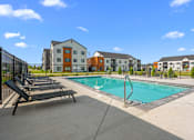 Thumbnail 40 of 64 - A swimming pool surrounded by lounge chairs and view of apartment buildings at Silverbrook Apartments, Kalispell
