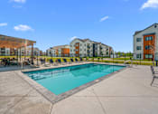 Thumbnail 41 of 64 - A swimming pool surrounded by lounge chairs and view of outdoor lounge area and apartment buildings at Silverbrook Apartments, Kalispell