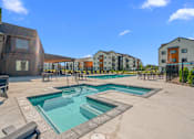 Thumbnail 39 of 64 - Soothing spa with view of the pool surrounded by pool chairs and tables at Silverbrook Apartments, Kalispell, 59901