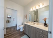 Thumbnail 17 of 64 - A bathroom with a toilet, sink, and mirror. at Silverbrook Apartments, Montana