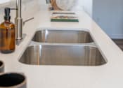Thumbnail 6 of 64 - A kitchen sink with a silver faucet and a brown bottle on the counter. at Silverbrook Apartments, Montana, 59901