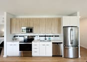 Thumbnail 4 of 23 - A modern kitchen with a stainless steel refrigerator, oven, and sink.