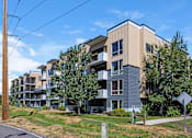 Thumbnail 21 of 23 - A modern apartment building with a mix of beige and grey exterior.