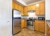 Thumbnail 10 of 23 - A kitchen with wooden cabinets and a stainless steel refrigerator.