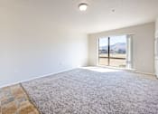 Thumbnail 13 of 23 - A spacious room with a large rug and a view of the outdoors through a sliding glass door.