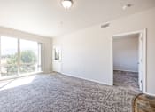 Thumbnail 9 of 23 - A spacious room with a carpeted floor and sliding glass doors leading to a balcony.