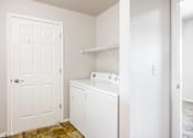 Thumbnail 17 of 23 - A white door is on the left of a white washing machine.